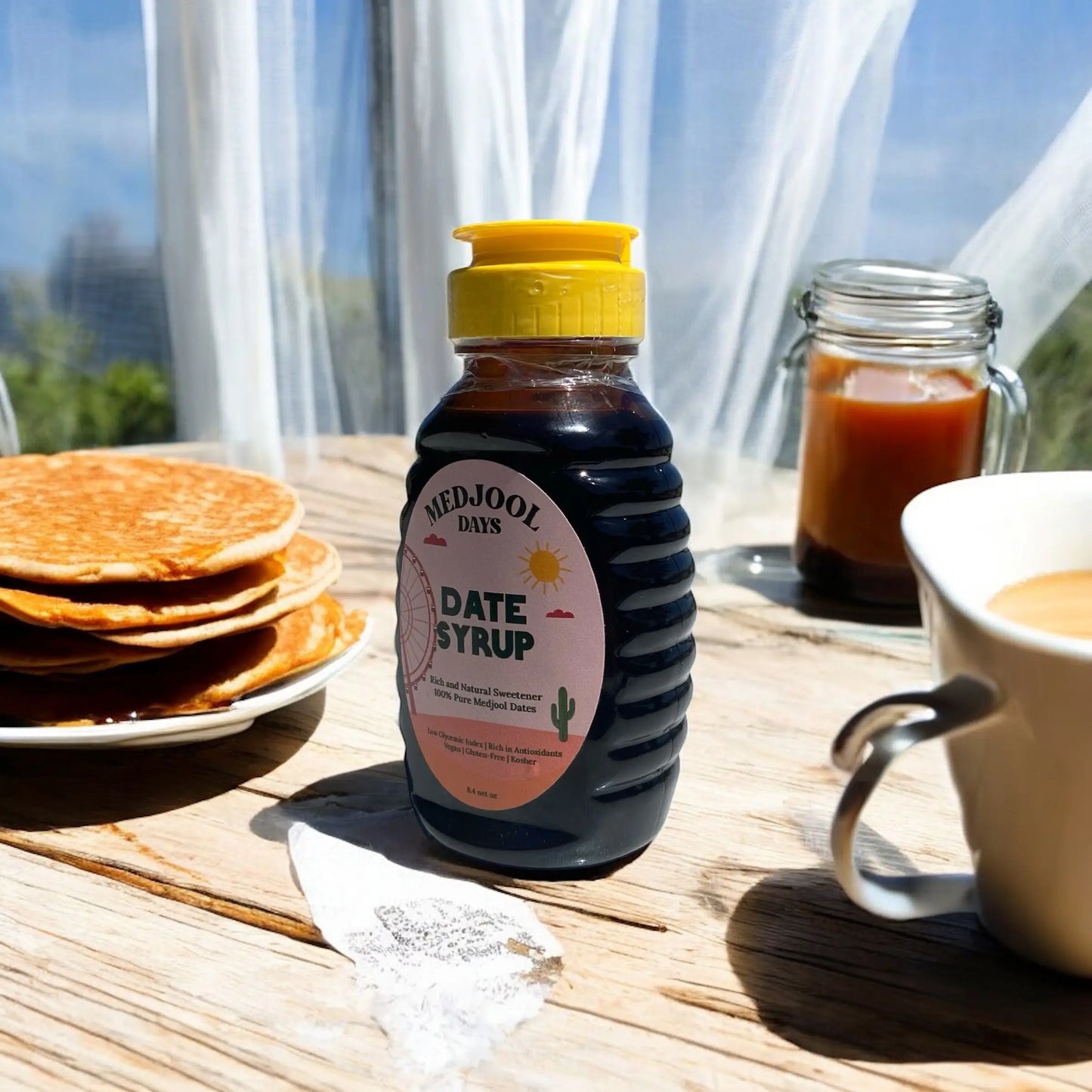 Medjool Days organic date nectar bottle on wooden table with pancakes and coffee, natural sweetener from Medjool dates.