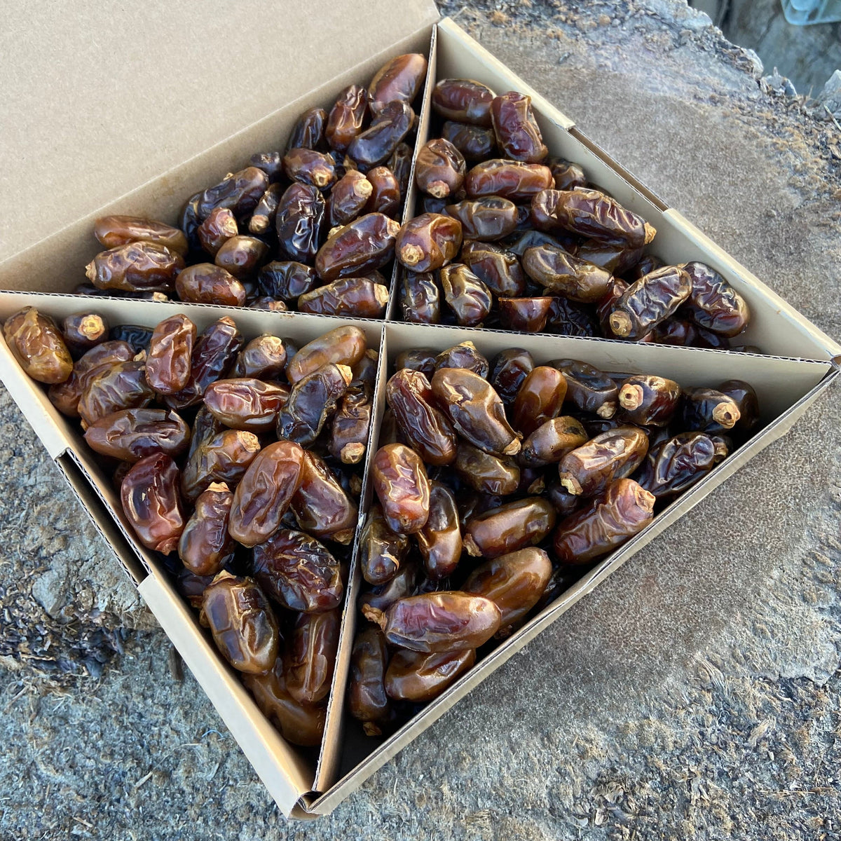 Box of Halawi Dates on a stone surface