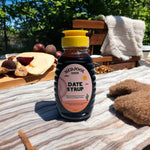 Premium Medjool Days date syrup bottle outdoors with figs and coffee – rich, all natural Medjool dates syrup.