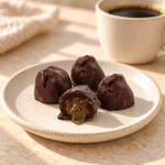 Coffee chocolate Medjool dates on a plate beside coffee