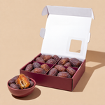 Open Medjool Days box with plump Rutab dates and a torn date in a bowl