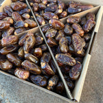 Box filled with dried Halawi Dates on a concrete surface