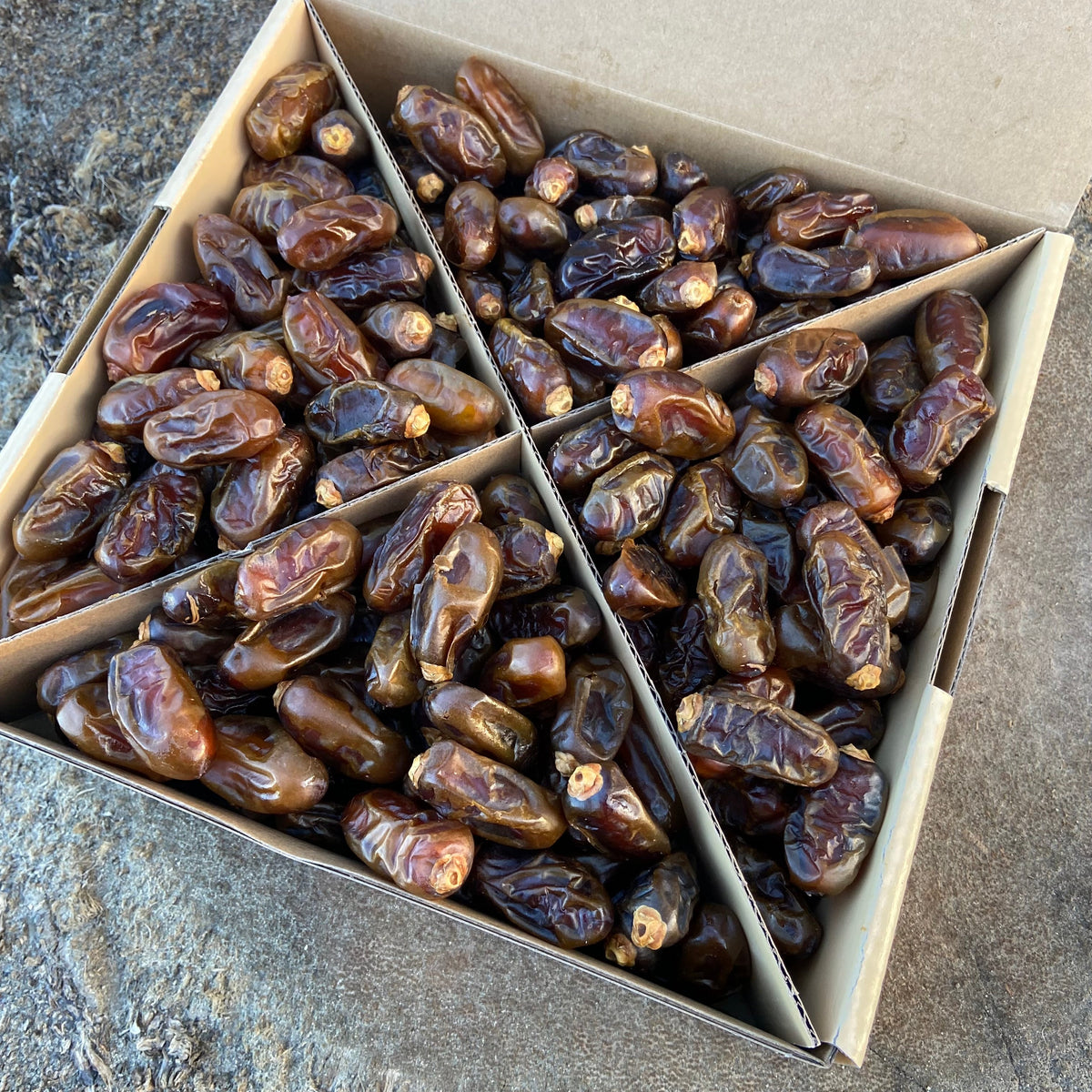 Box of Halawi Dates on a stone surface