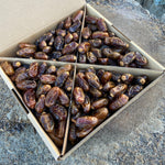 Box of Halawi Dates on a stone surface